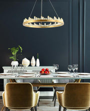 round gold chandelier with crystal obelisks over dining room table with gold chairs
