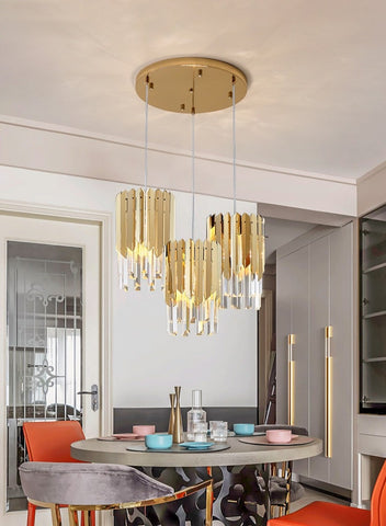 three gold pendants with clear crystal and round base in dining area at differing heights