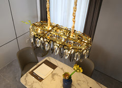 oval shaped crystals on oval chandelier with gold finish hanging over marble topped dining table