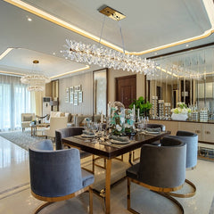 long crystal chandelier hanging over dining room table with barrel chairs