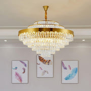 gold round conical crystal chandelier with feather wall art in background