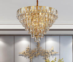 gold conical crystal chandelier illuminated with wall art in back 