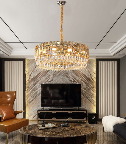 round champagne crystal chandelier hanging over coffee table in front of marble feature wall