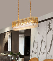 oval champagne crystal chandelier suspended over dining room table with marble feature wall in background