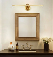 Gold wall sconce with LED bulb and artful detail on the canopy hanging over bathroom mirror