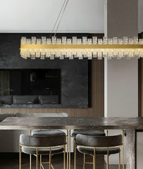 long rectangular water pattern glass chandelier with with gold band suspended over marble bar