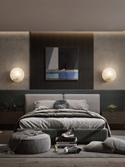 two post modern glass and bronze finish circular wall sconces flanking a bed
